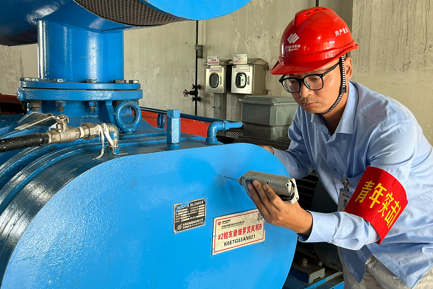 图为青年人员检查粗灰磨制系统设备运行情况