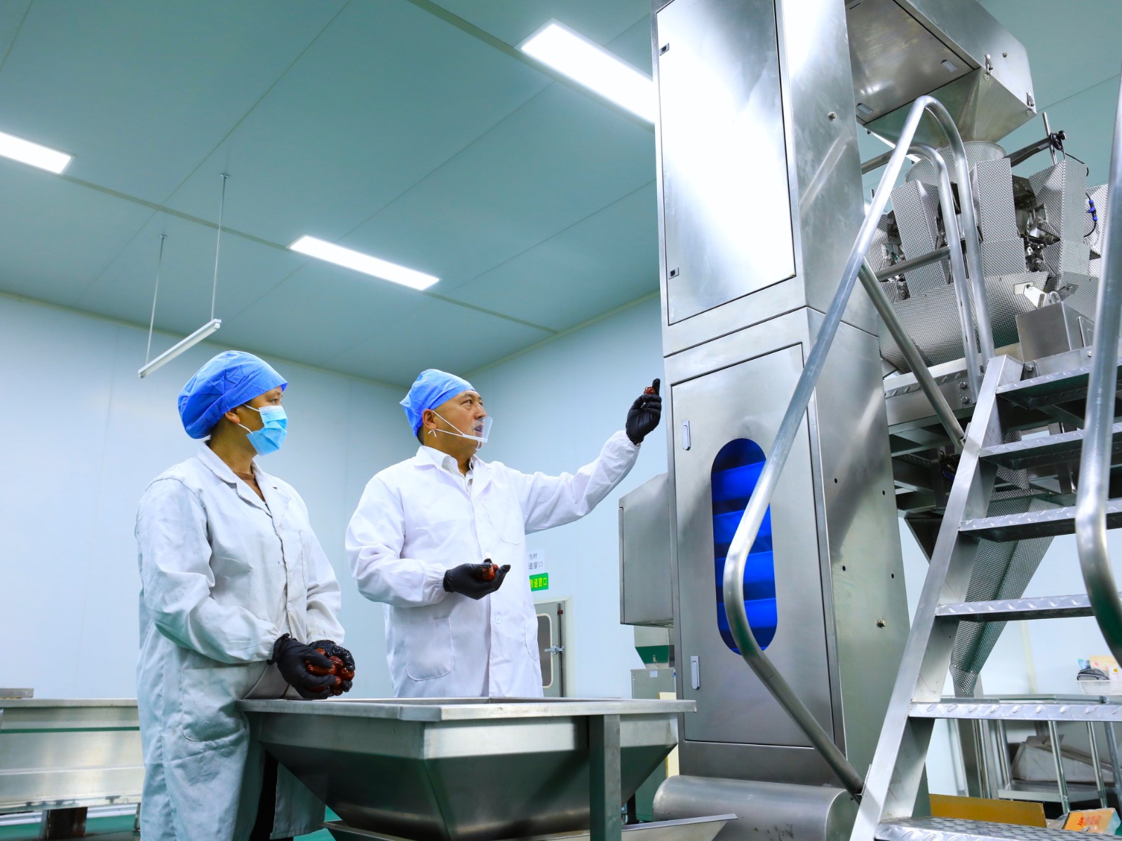 图为驻村队员正在指导风兮果园员工正确使用干果分选机姚煜峰摄